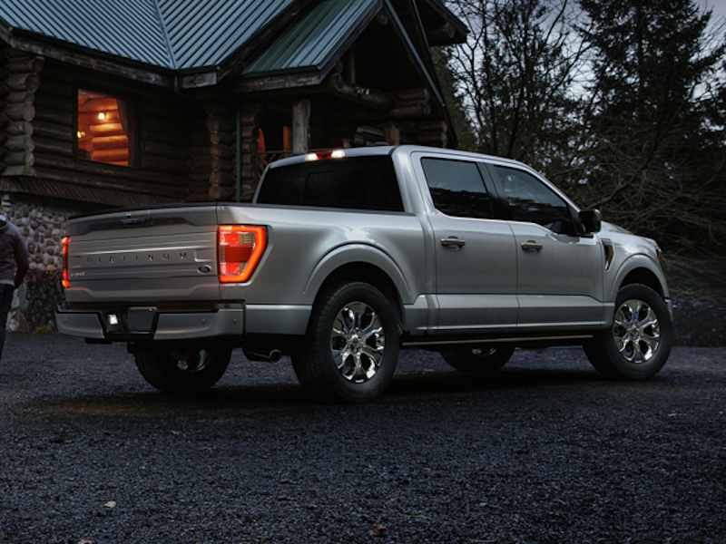 The rear end of a 2024 Ford F-150 in front of a log cabin